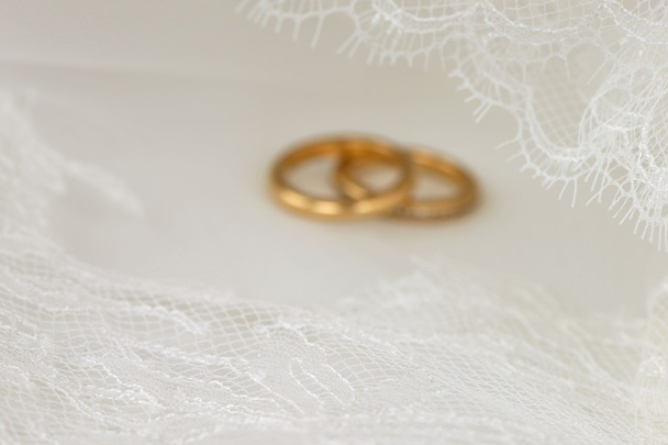 Άσπρο γαμήλιο δαντέλα με χρυσά δαχτυλίδια στο παρασκήνιο - Φωτογραφία, εικόνα