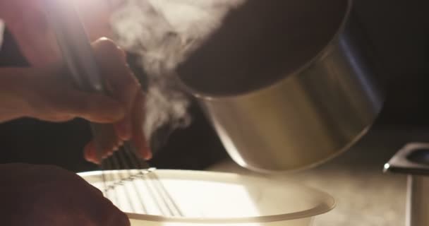 Super slow motion macro of a middle aged chef pouring hot milk from a pot in a bowl (close up) - Záběry, video