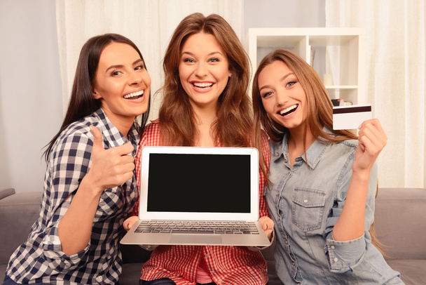 Cheerful girls showing laptop, bank card and gesturing - Foto, immagini