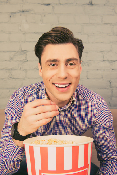 Portrait of happy smiling man eating popcorn at home - Fotoğraf, Görsel