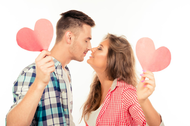 Happy couple in love holding two paper hearts kissing each other - Фото, изображение