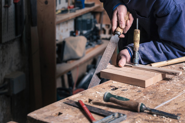 Tischler, der mit einer Feile an einem Holzschneidebrett arbeitet - Foto, Bild