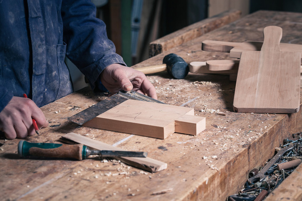 Carpintero trabajando en una tabla de cortar de madera con lápiz y regla
 - Foto, Imagen