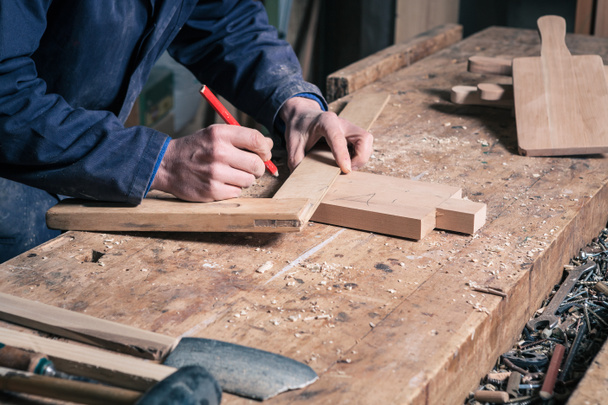 Carpintero trabajando en una tabla de cortar de madera con lápiz y regla
 - Foto, imagen