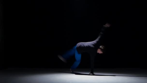 Talanted young dancer man dancing breakdance on black - Felvétel, videó