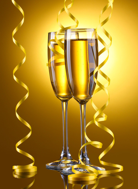 Glasses of champagne and streamer on yellow background - Фото, зображення