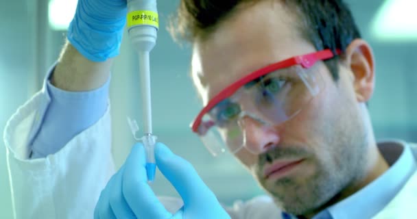 young and charming doctor accomplishes some routine medical procedures and equipped professional in the laboratory researcher with professional development material - Záběry, video