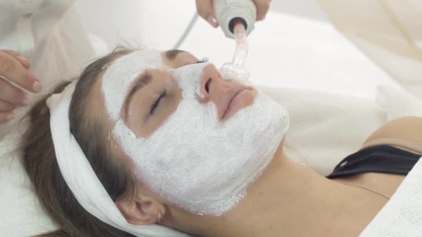 Close-up darsonvalization meisje gezicht met klei masker in salon. Cosmetische procedure. - Video