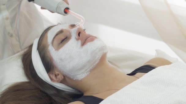 Close-up darsonvalization gezicht van het meisje met het masker in salon. Cosmetische procedure - Video