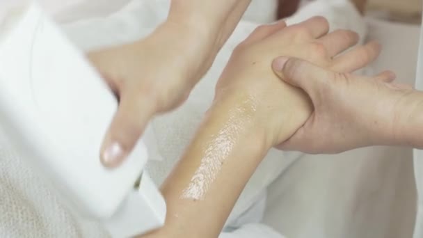 El primer plano de las manos cosmetólogas ponen la cera en la muñeca de la mano de la muchacha en el salón de belleza
 - Metraje, vídeo