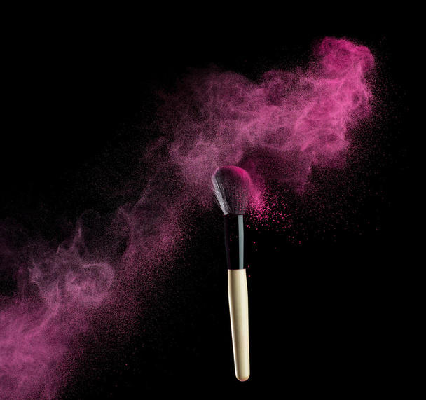 Make-up brush with pink powder explosion on black background - Fotó, kép