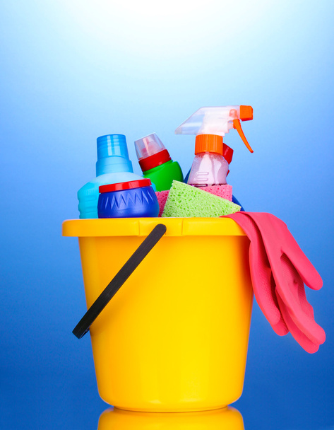 Bucket with cleaning items on blue background - Photo, image