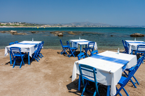 海岸のロードス島、ギリシャの Kolympia 町で伝統的なギリシャのタベルナで椅子とテーブル. - 写真・画像