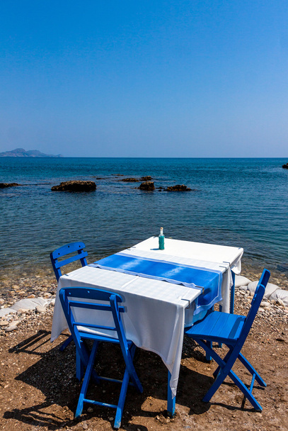 海岸のロードス島、ギリシャの Kolympia 町で伝統的なギリシャのタベルナで椅子とテーブル. - 写真・画像