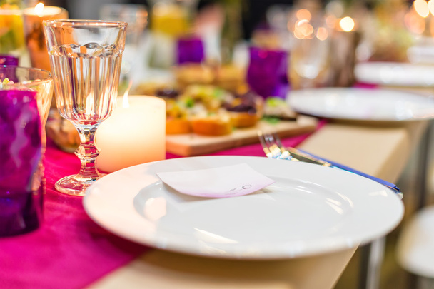 Koristeltu pöytä valmiina päivälliselle. Kauniisti sisustettu pöytä, jossa on kukkia, kynttilöitä, lautasia ja lautasliinoja häät tai muu tapahtuma ravintolassa.
. - Valokuva, kuva