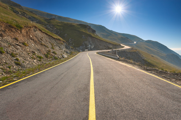 Conduciendo por un camino de montaña vacío hacia el sol
 - Foto, Imagen