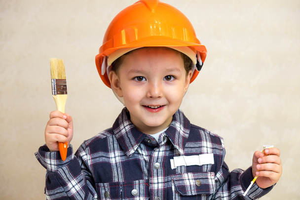 boy builder in a helmet and with a brush. - Zdjęcie, obraz