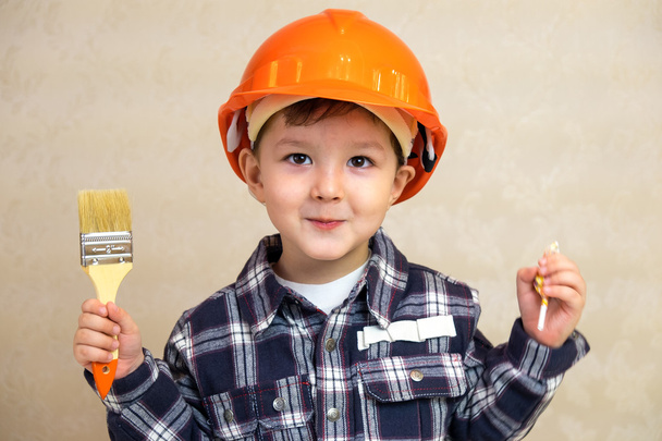 boy builder in a helmet and with a brush. - Zdjęcie, obraz
