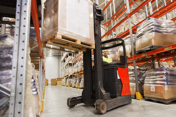 man on forklift loading cargo at warehouse - Foto, Bild