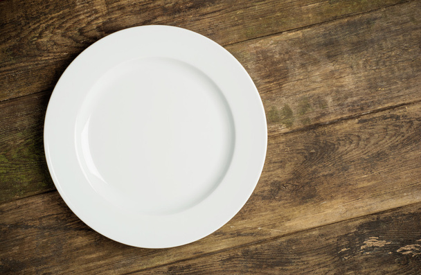Empty white plate on rustic wooden background - Foto, afbeelding