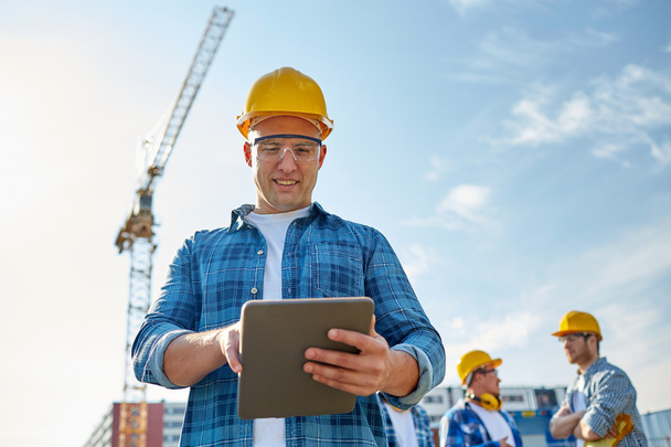 builder in hardhat with tablet pc at construction - Φωτογραφία, εικόνα