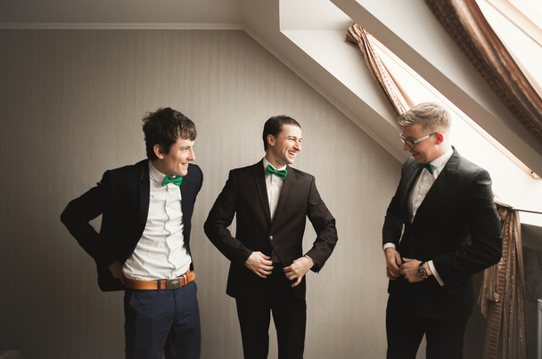 Happy friends helps stylish groom getting ready for his wedding day - Foto, immagini