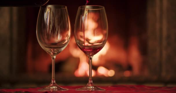 Pouring glasses of red wine by fireplace - Materiał filmowy, wideo