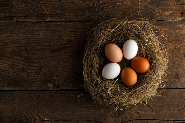 Chicken eggs in a nest on a wooden rustic background - Photo, Image
