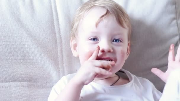 Маленький мальчик ест шоколад и размазанный рот - Кадры, видео