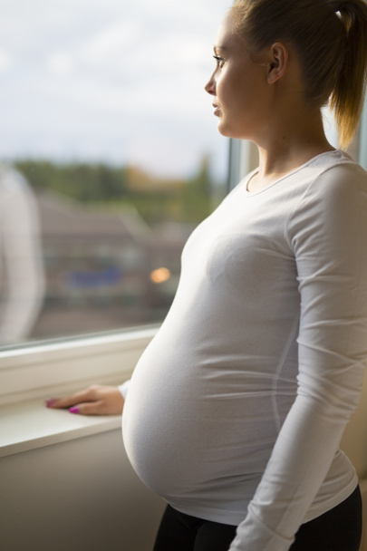 Promyšlené těhotná žena při pohledu z okna - Fotografie, Obrázek