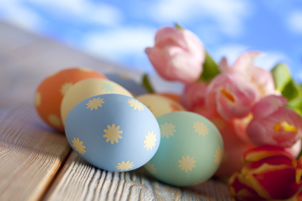 Huevos de Pascua en colores pastel y tulipanes de colores sobre fondo azul
 - Foto, imagen