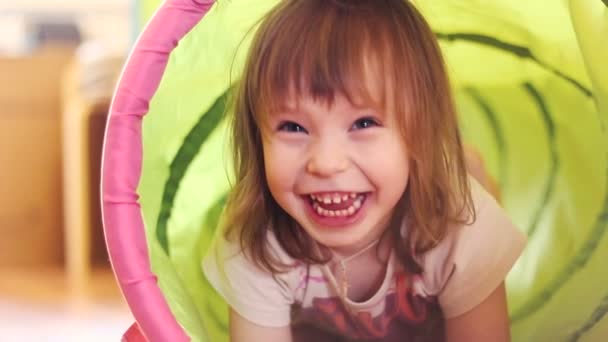 Szczęśliwa dziewczynka śmiejąc się w tunelu zabawka dla dzieci - Materiał filmowy, wideo