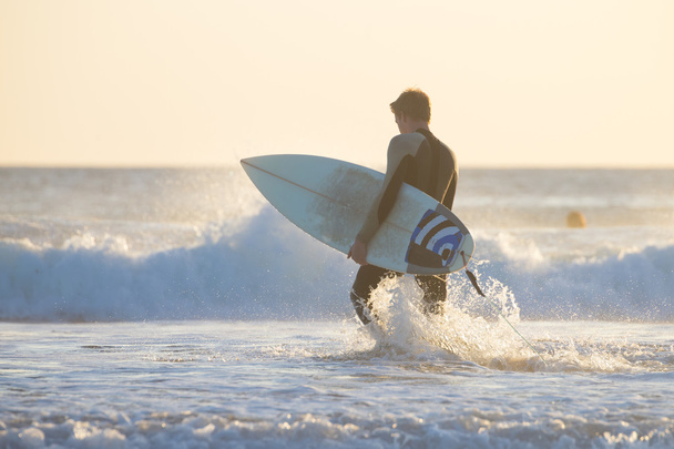 Silhouette of surfer on beach with surfboard. - Foto, Imagen