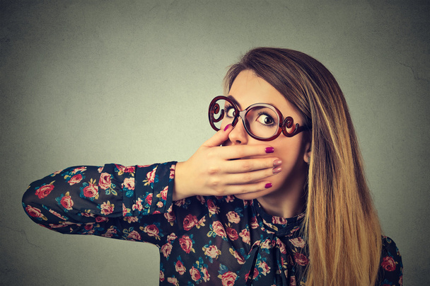 Closeup portrait of scared young woman in glasses covering with hand her mouth - Foto, imagen