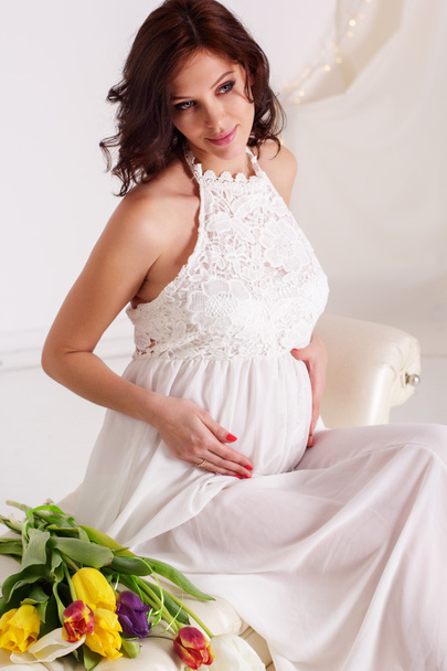 Красивая беременная девушка держит цветы тюльпана
 - Фото, изображение