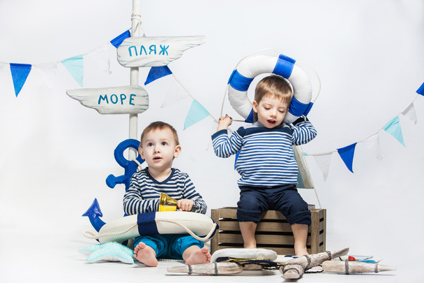two little boys in striped dress as sailors , lifebuoys , white  - Фото, изображение