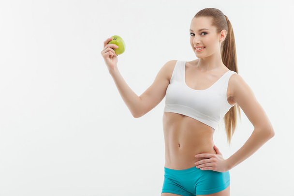 Attractive young sportswoman with a green fruit - Fotoğraf, Görsel