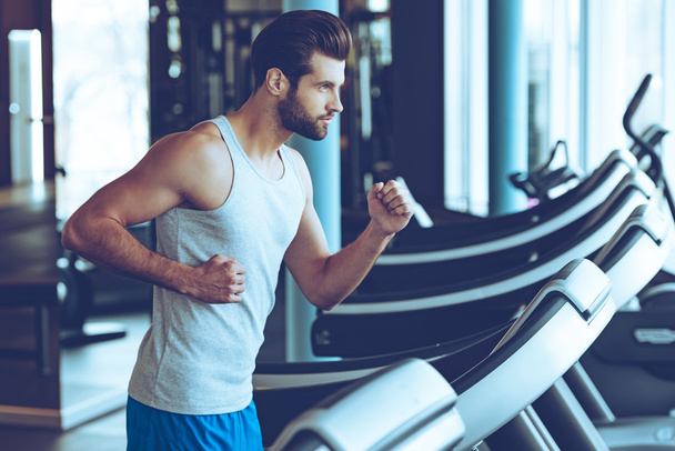 young man in sportswear running on treadmill - Photo, image