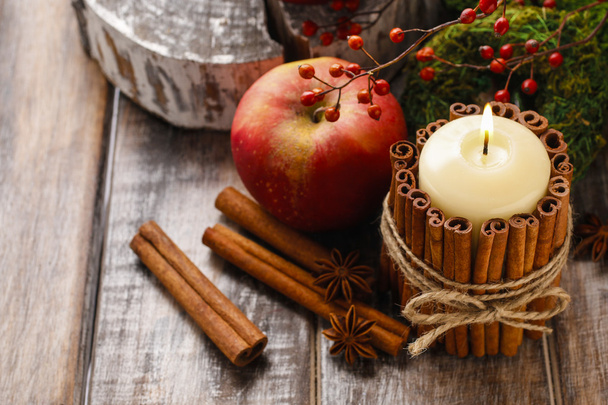 Candle decorated with cinnamon sticks and red apples - Фото, изображение