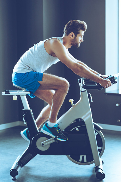 young man cycling at gym - 写真・画像