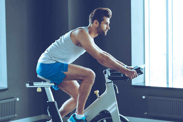 young man cycling at gym - 写真・画像