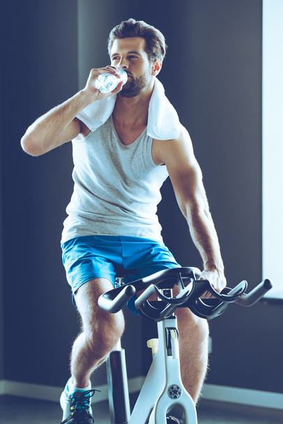 young man cycling at gym - Foto, afbeelding