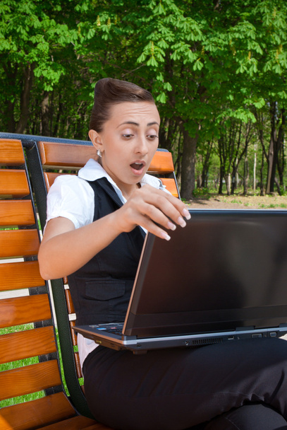 Verblüffte Frau mit Laptop auf Bank - Foto, Bild