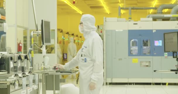 Trabajadores con trajes limpios en una instalación de fabricación de semiconductores
 - Metraje, vídeo