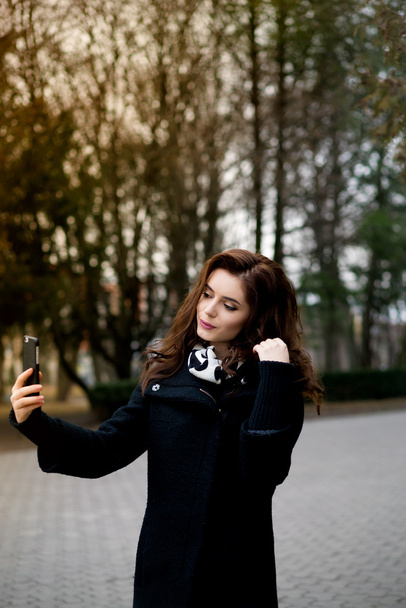 Beautiful young woman makes selfie in the park - Фото, зображення