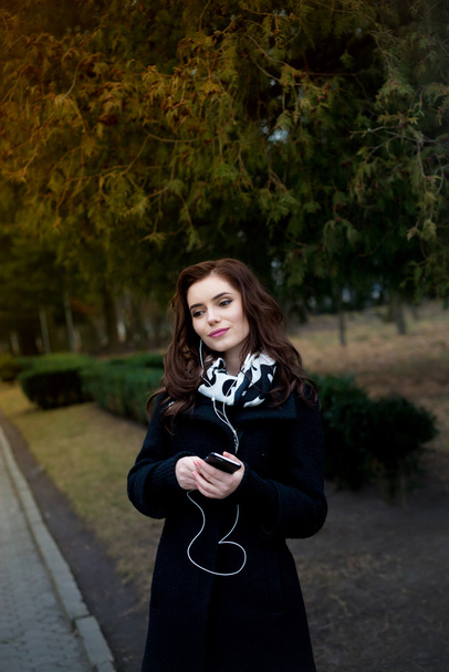 Beautiful girl listens to music in the park - Фото, изображение