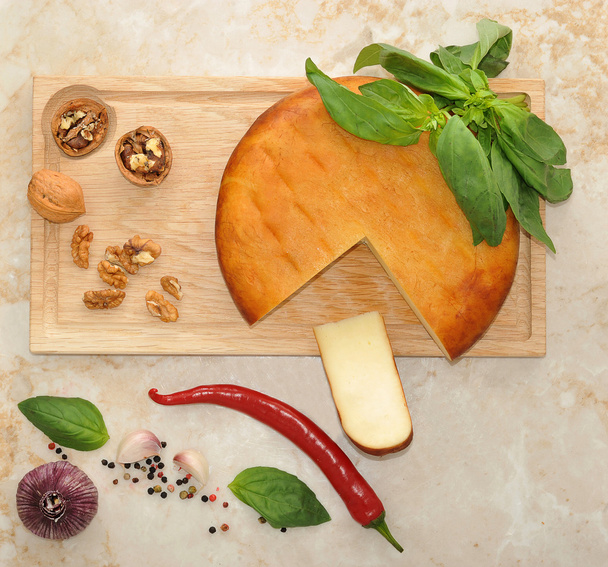 head of smoked Suluguni cheese on wooden Board with walnuts and  - Valokuva, kuva