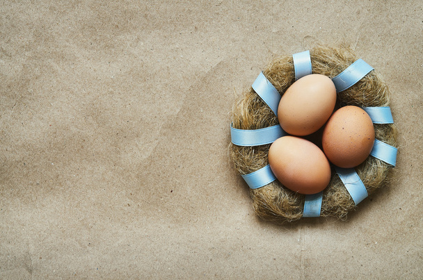 Corona de nido con huevos sobre fondo de papel ecológico artesanal. Plantilla postal de Pascua. Espacio para texto, copia, letras
. - Foto, imagen