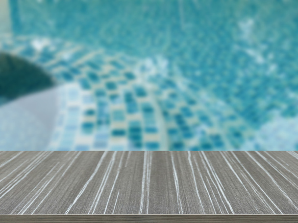 empty wooden table with water surface of the swimming pool blur  - Fotografie, Obrázek