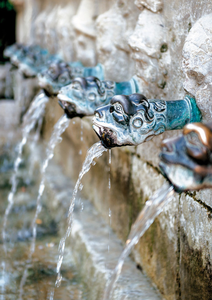 Детали фонтана; декоративные головки, плюющие водой в старый каменный фонтан
 - Фото, изображение